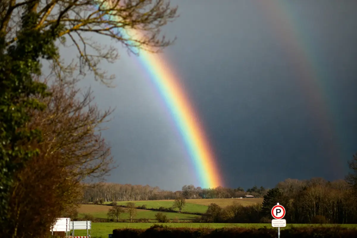 Arc-en-ciel vibrant sur paysage rural, explorant la signification de l'arc-en-ciel dans la nature