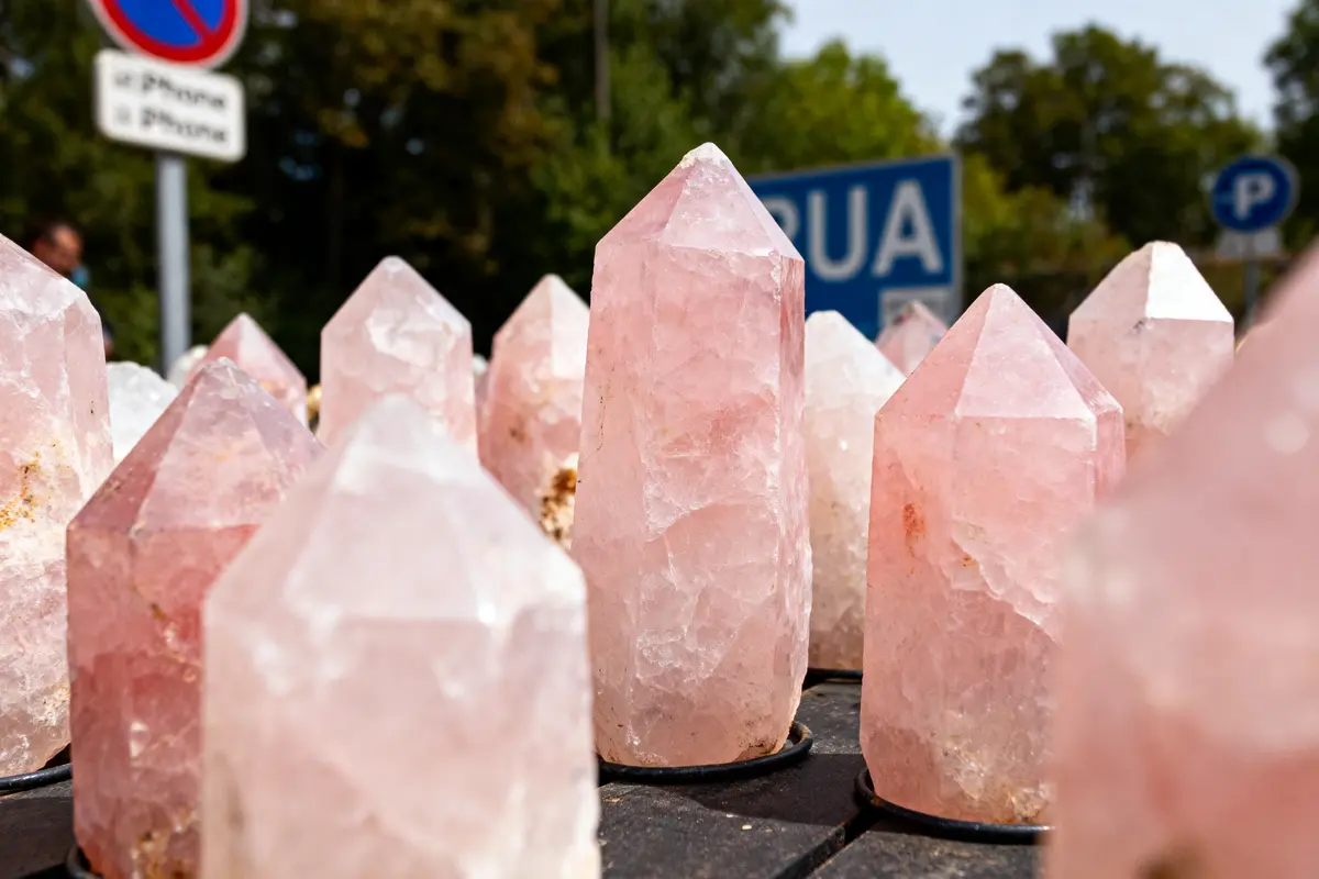 Cristaux de quartz rose exposés sur une table, panneau de signalisation en arrière-plan flou.