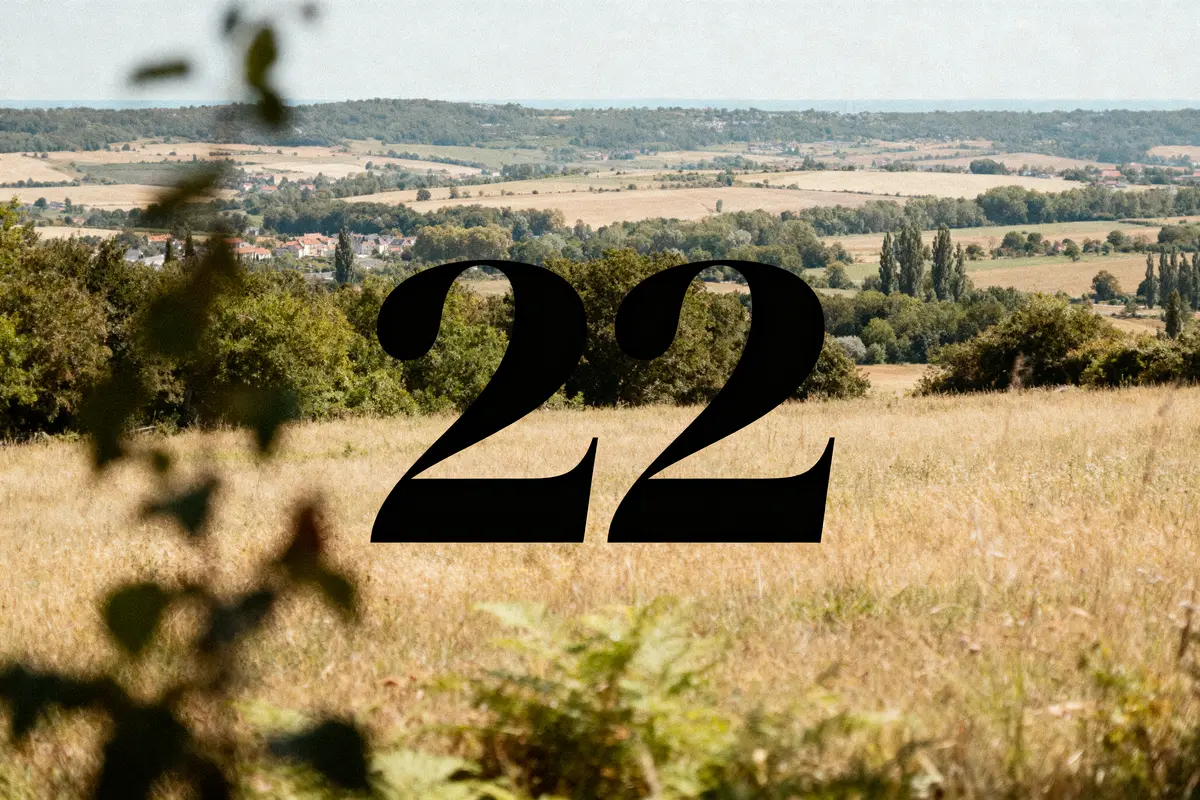 Paysage rural avec champs, collines, et grand chiffre 22 au centre.
